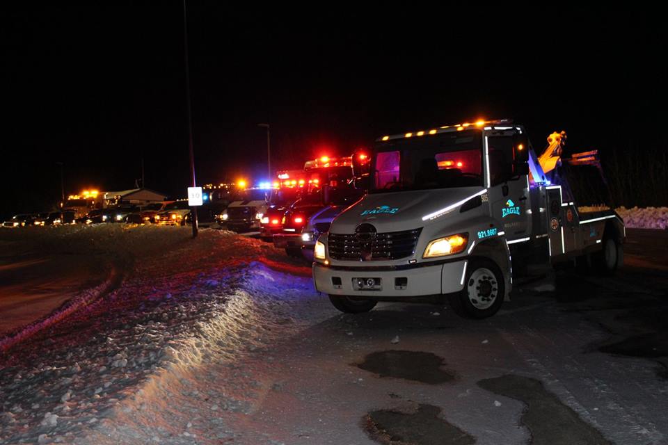 A picture at night of a bunch o tow trucks and other emergency vehicles for a rally or a fallen tow truck driver